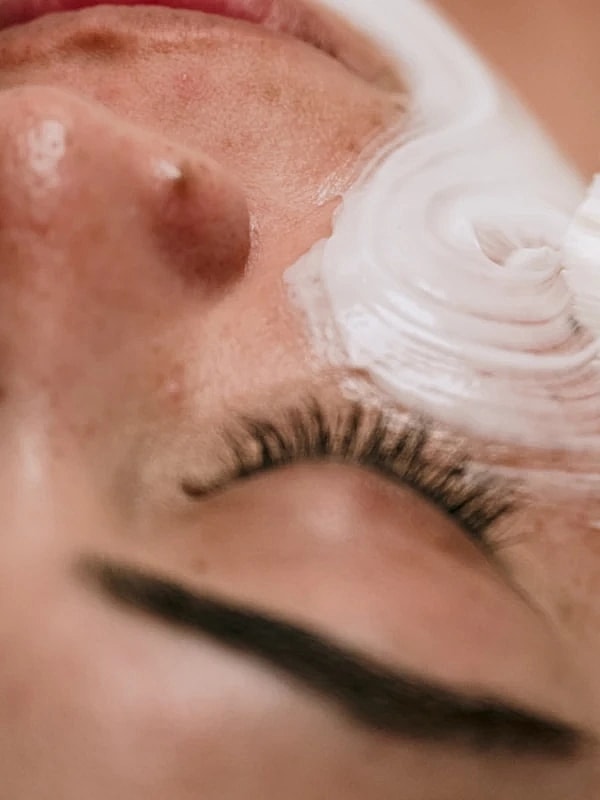 Facial treatment with cream on closed eyes.