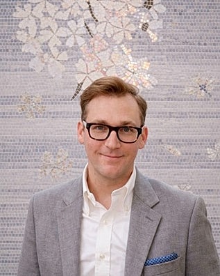 Man in glasses against decorative backdrop.