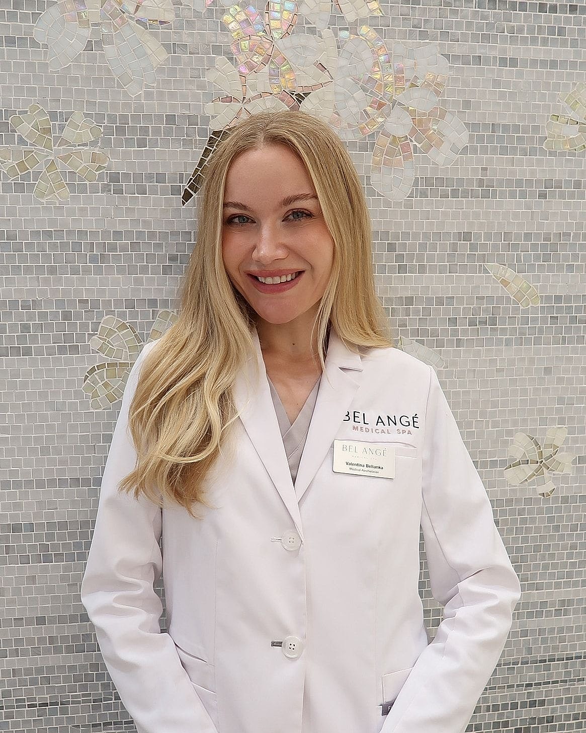 Woman in white coat at medical spa backdrop.